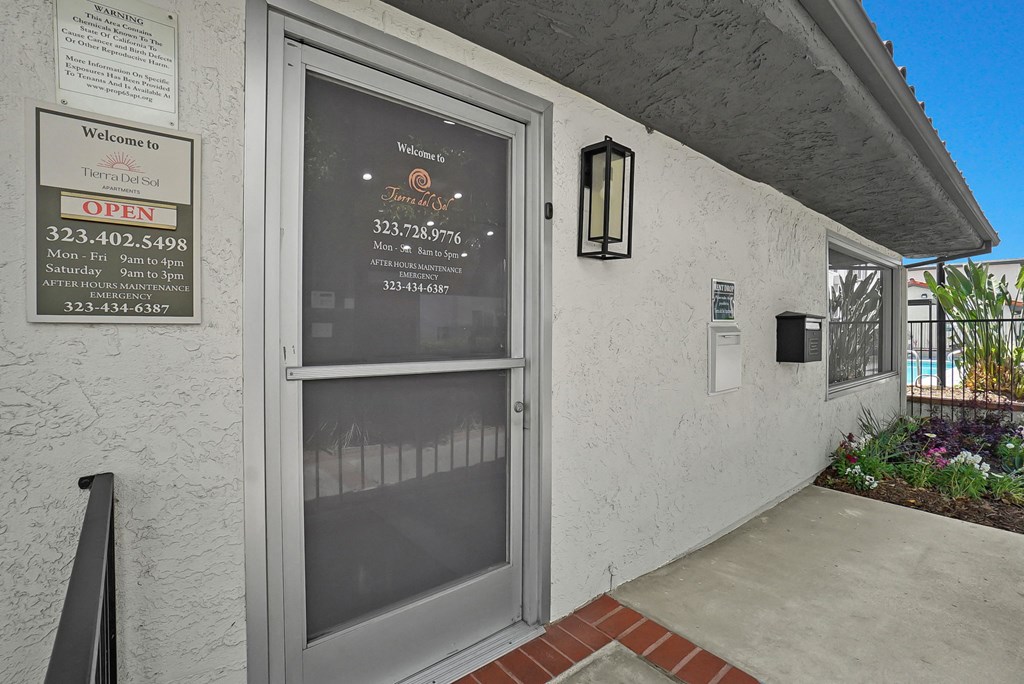 A building entrance with a glass door and a sign on the wall.