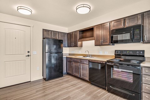 A kitchen with black appliances and wooden cabinets.