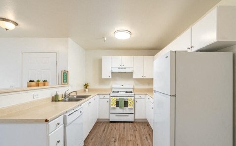 A kitchen with white cabinets and a wooden floor.