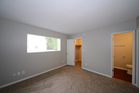 a bedroom with a window and a door to a bathroom
