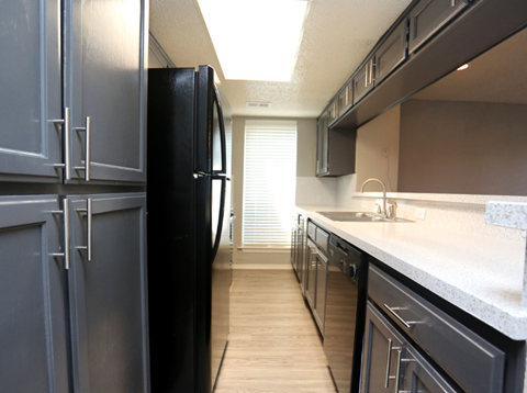 a kitchen with dark cabinets and a sink and a refrigerator