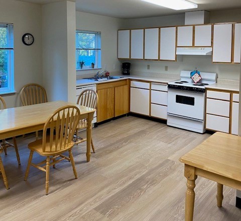A kitchen with wooden chairs and cabinets.