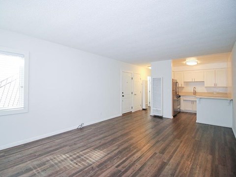 an empty living room and kitchen with wood floors