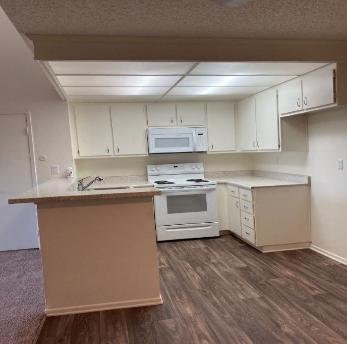 A kitchen with white cabinets and a white microwave above the counter.