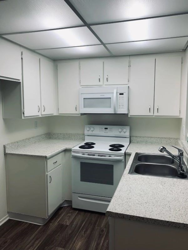 A kitchen with white cabinets and a white microwave above the stove.