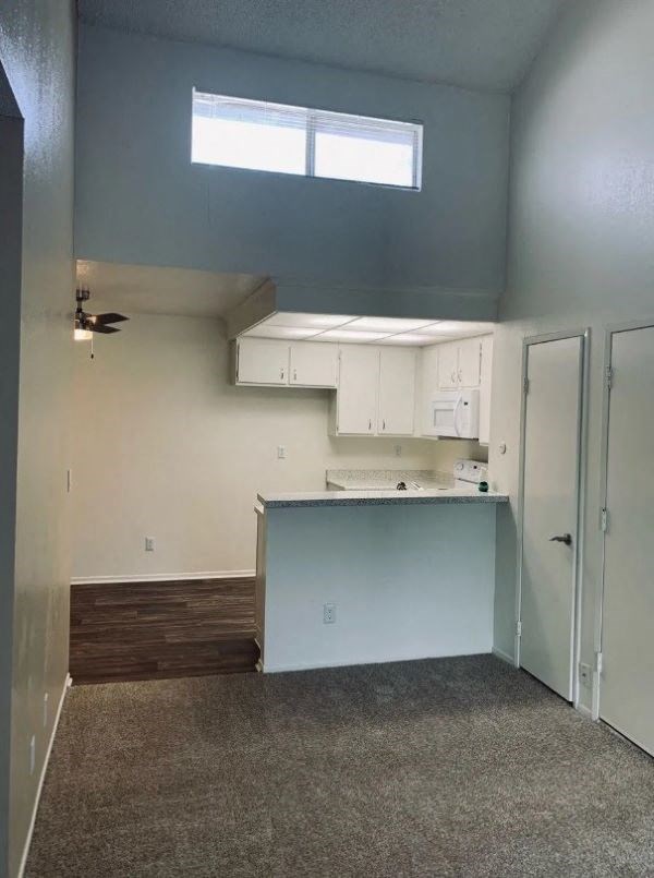 A room with a window, a ceiling fan, and a counter.