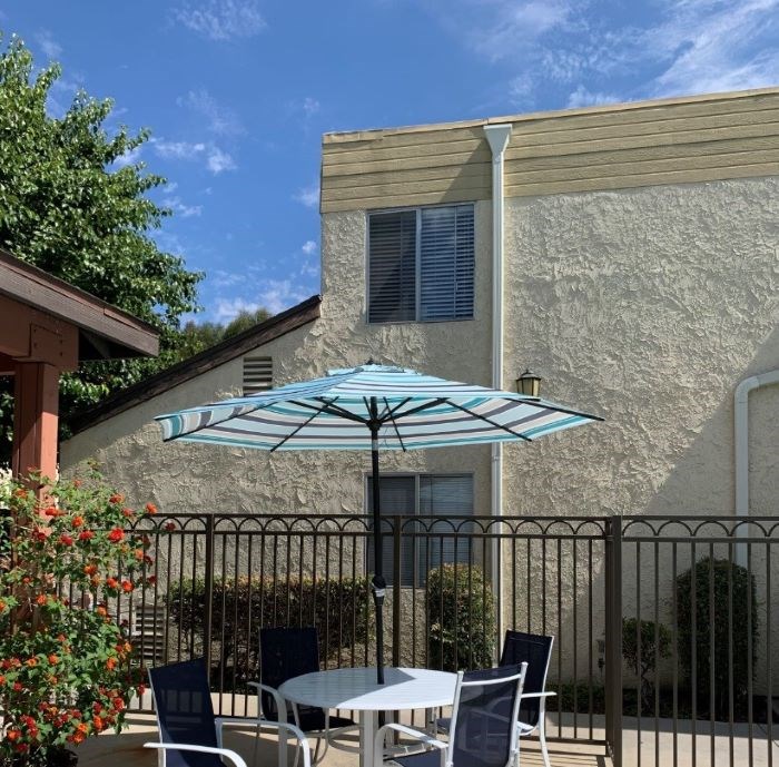 A patio with a table, chairs, and an umbrella.
