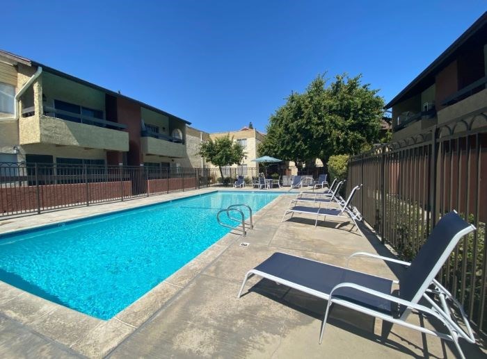 A pool surrounded by chairs and a fence.