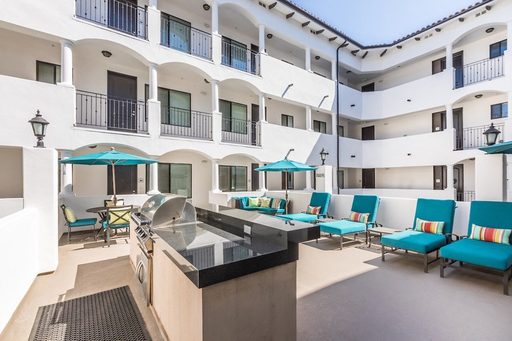 a large white building with blue chairs and umbrellas in front of it