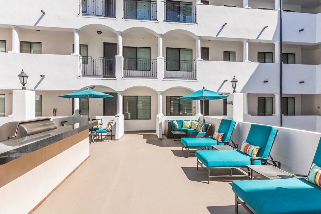 a hotel patio with blue lounge chairs and umbrellas