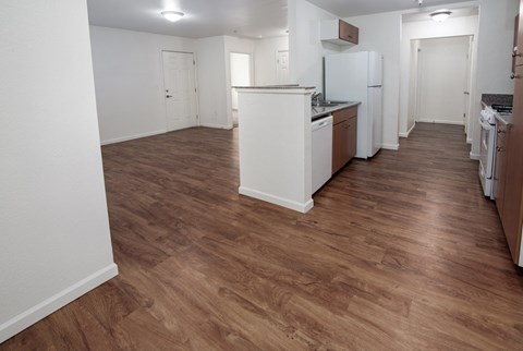 A kitchen with white appliances and wooden floors.