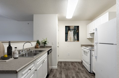 A kitchen with a white refrigerator and a painting hanging on the wall.