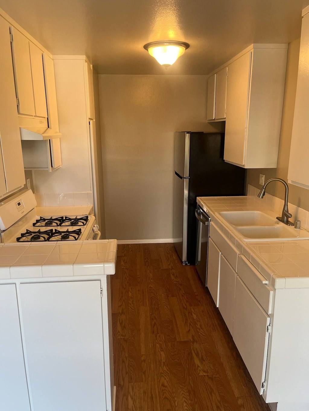 A kitchen with a black refrigerator and white cabinets.