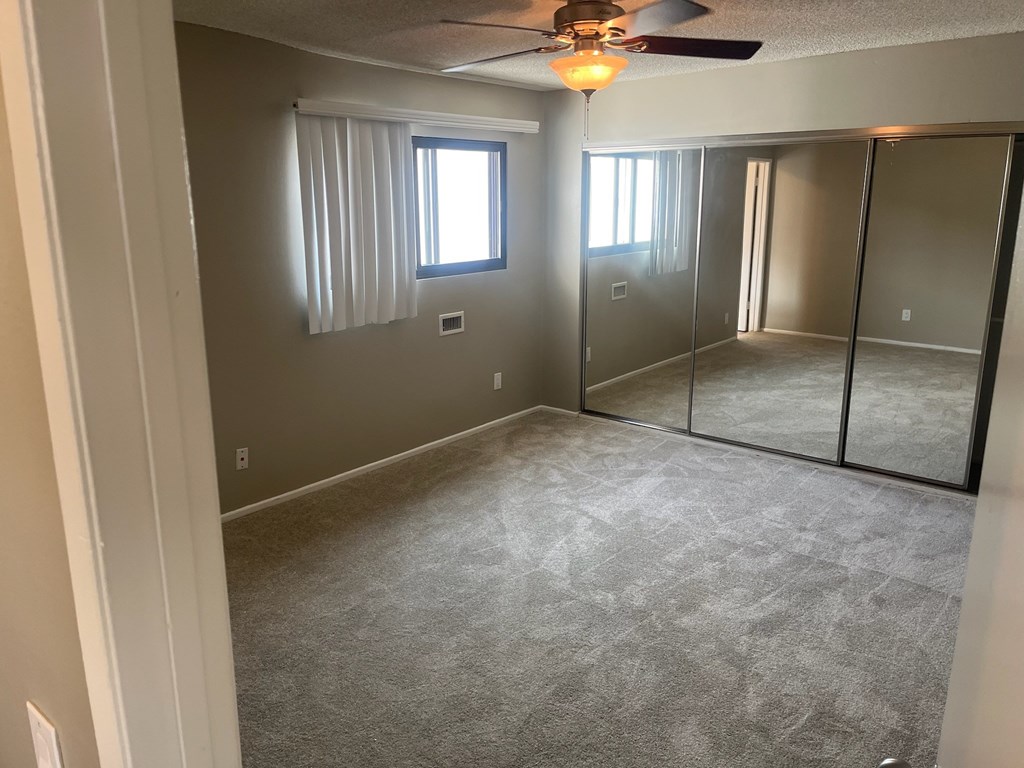 A room with a ceiling fan and a window with blinds.