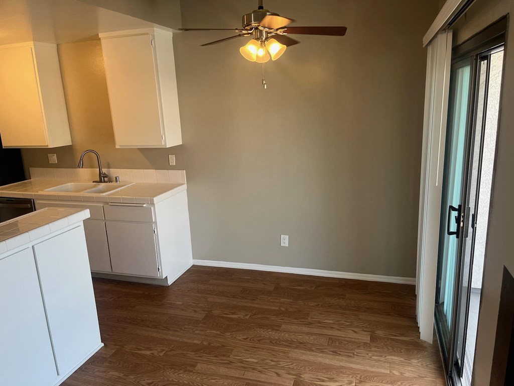 A kitchen with white cabinets and a ceiling fan.