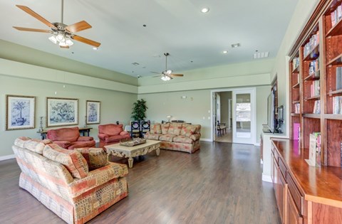 A living room with a sofa set and a ceiling fan.
