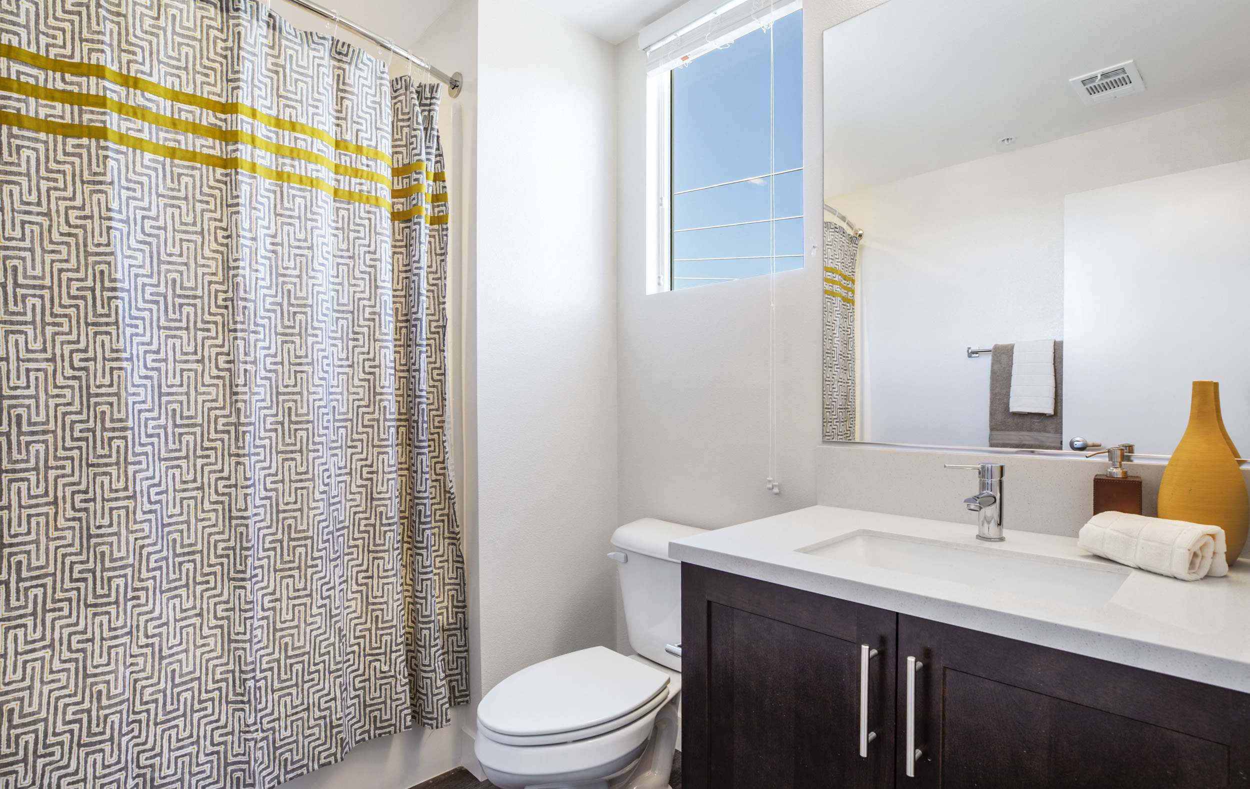 YOLO East bathroom vanity, toilet, and shower with window