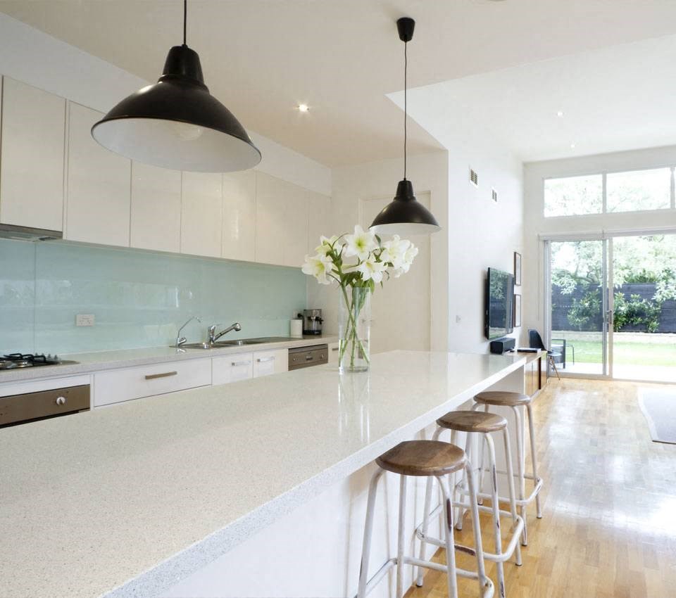 a white kitchen with a long counter and stools