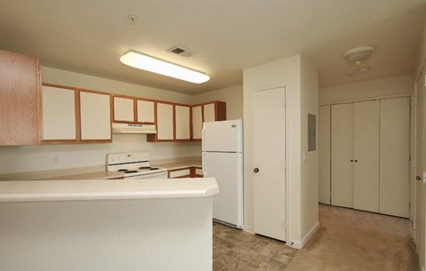 Englewood, CO Apartments - Centennial East - kitchen with white appliances and wooden cabinets.