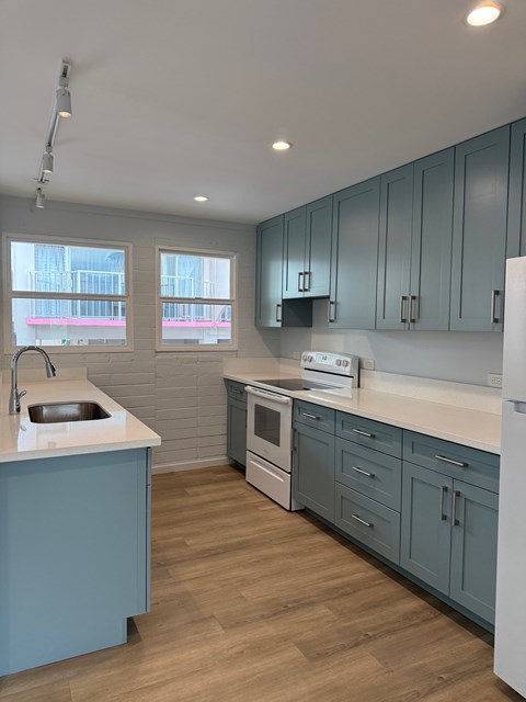 A kitchen with a white counter top and blue cabinets.