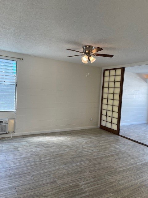 A room with a ceiling fan and light fixture, a window with blinds, and a wooden floor.
