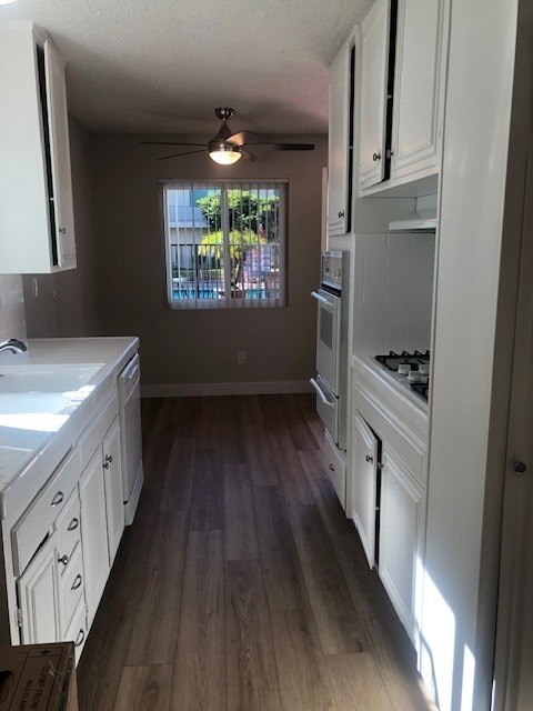 A kitchen with white cabinets and a window.