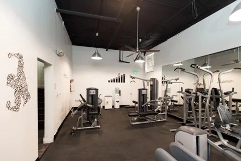 A gym with a variety of equipment including treadmills, weights, and exercise machines.