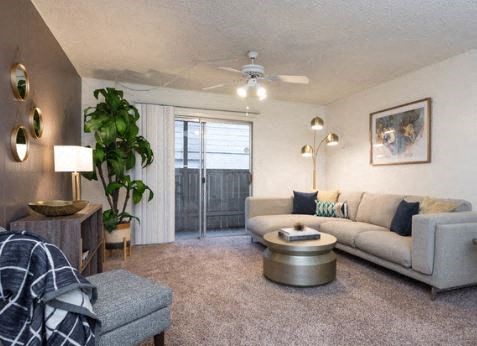 A living room with a grey sofa, a wooden side table, and a ceiling fan.
