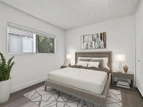 A bedroom with a large bed and a plant in a white pot.