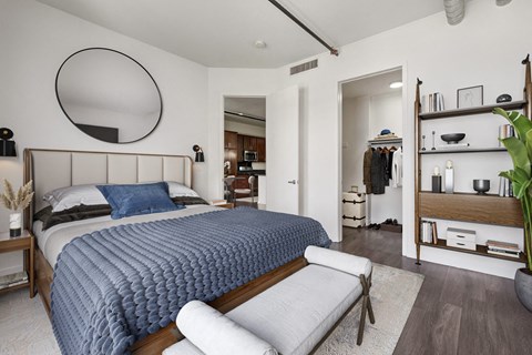 A bedroom with a large bed and a round mirror on the wall.