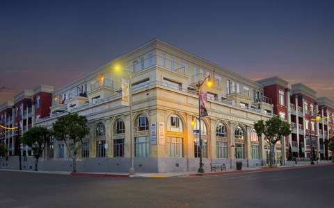 A large, well-lit building with a red awning and a flag on top.