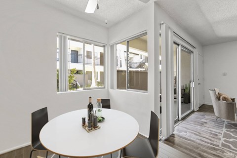 A dining room with a table set for two and a view of a balcony outside.