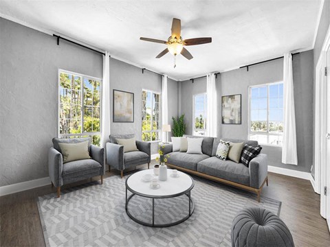 A living room with a grey couch, a coffee table, and a ceiling fan.