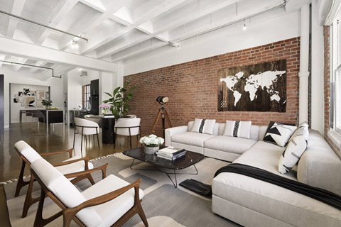 A living room with a white couch and a world map on the wall.