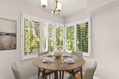 A dining room with a table set for two and a chandelier hanging from the ceiling.