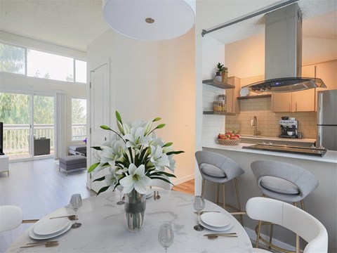 A kitchen with a table set for two with a vase of flowers on it.