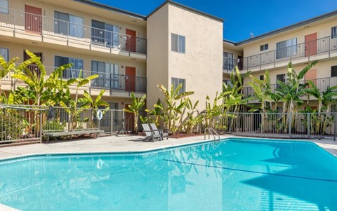 A swimming pool in front of a building with a balcony.