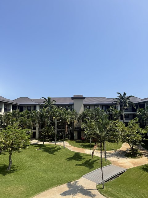 A large white building with a grey roof and a green lawn in front.