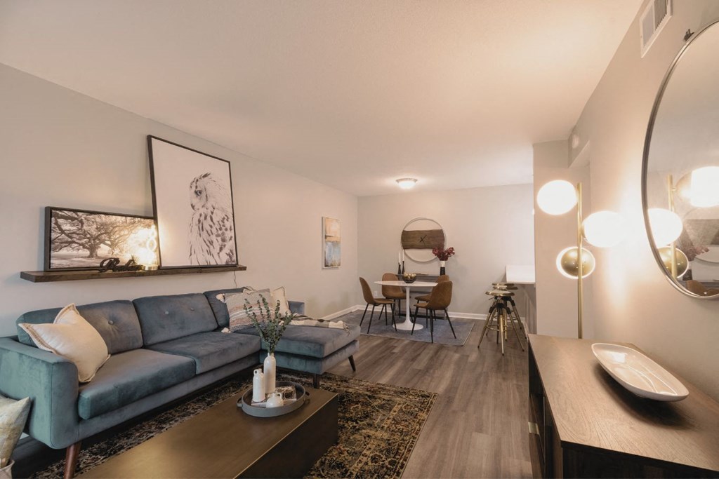 a living room with a couch a coffee table and a dining room table in the background