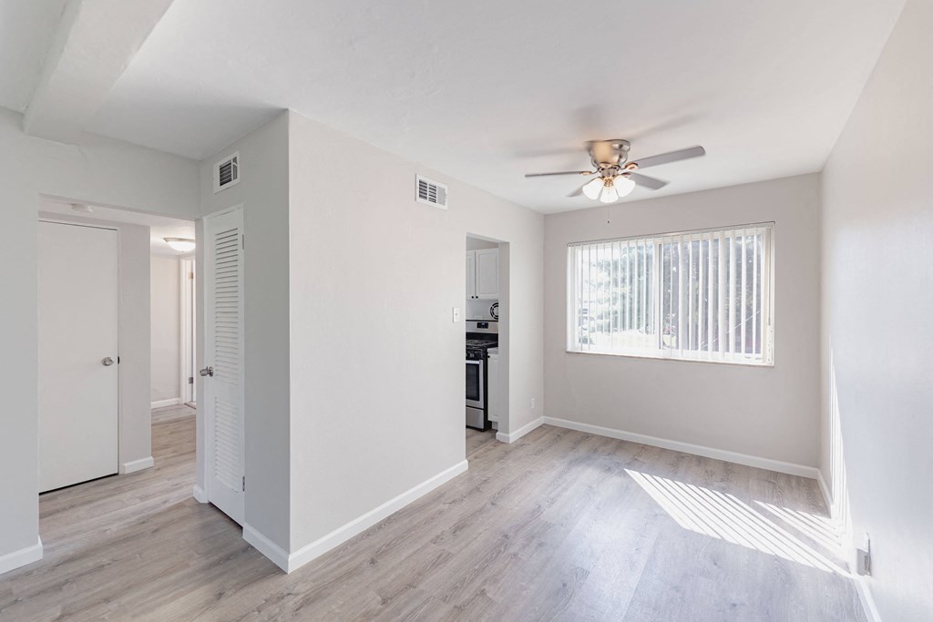 an empty living room with white walls and a ceiling fan