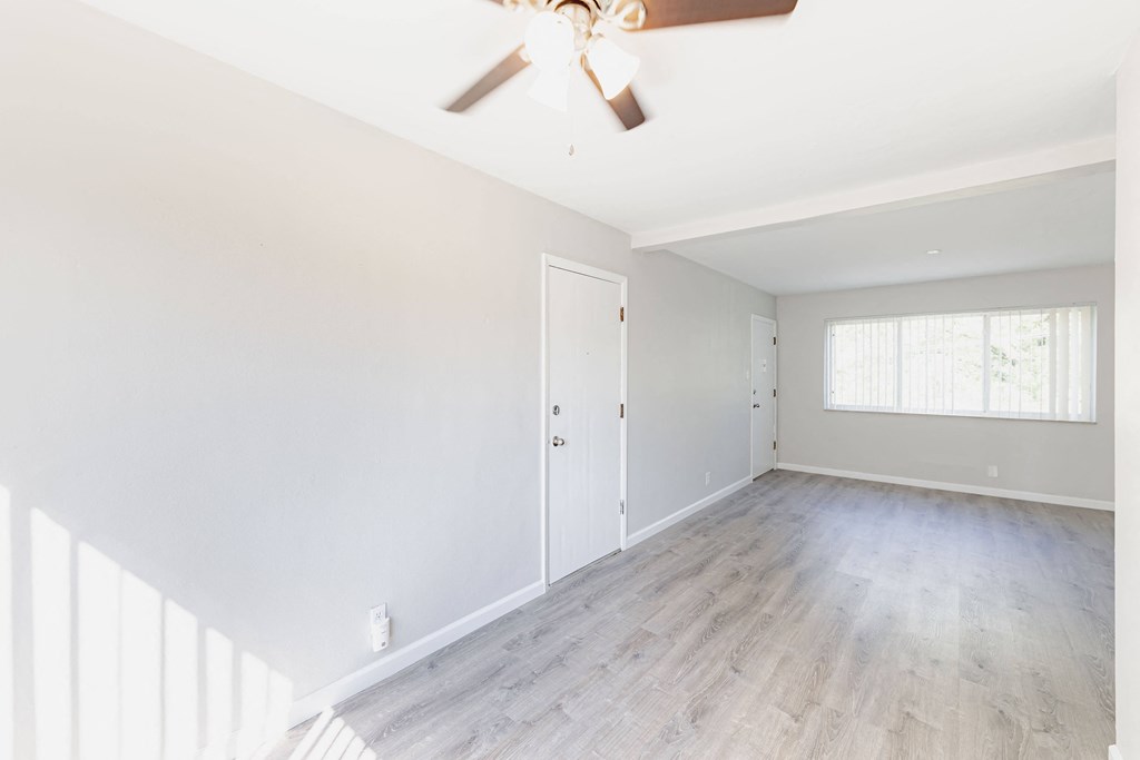 an empty room with white walls and a ceiling fan