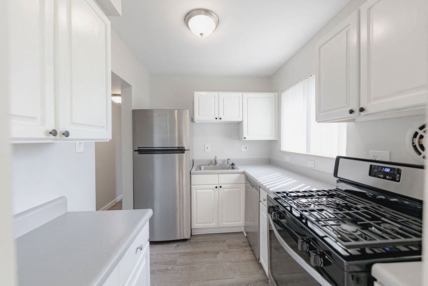 a white kitchen with stainless steel appliances and white cabinets
