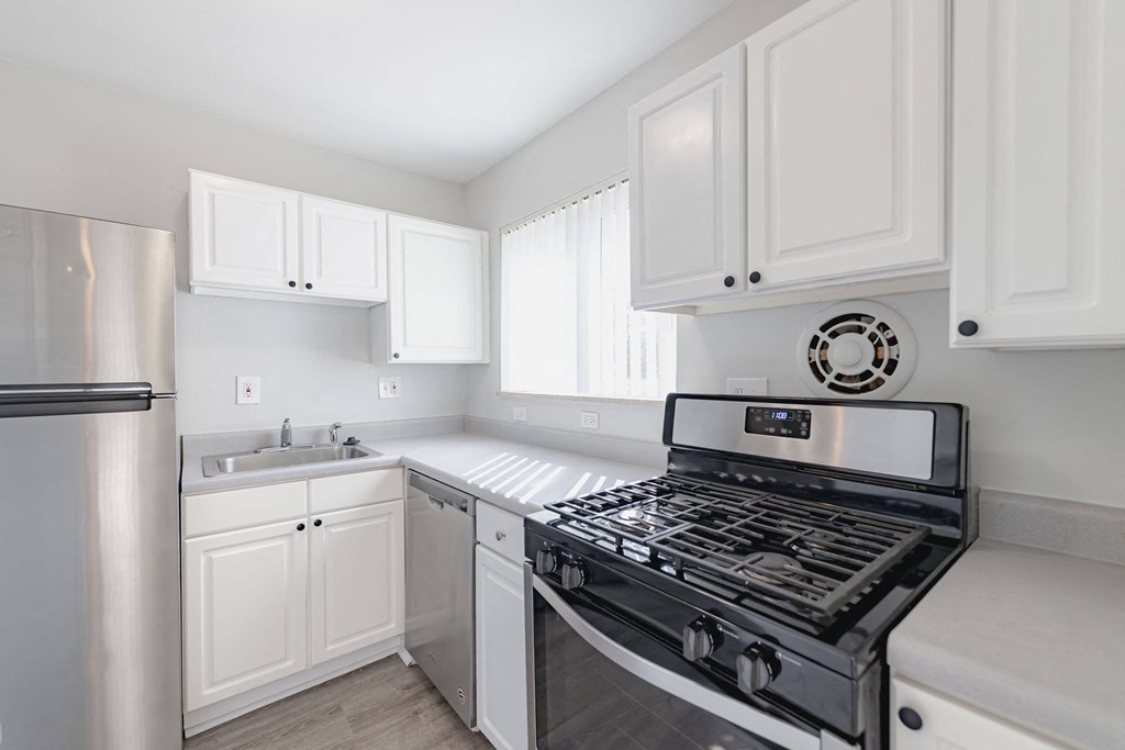 a kitchen with white cabinets and a stove and a sink