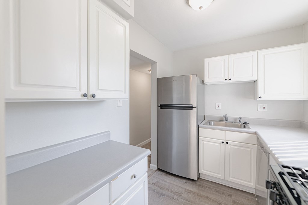 an empty kitchen with white cabinets and a stainless steel refrigerator