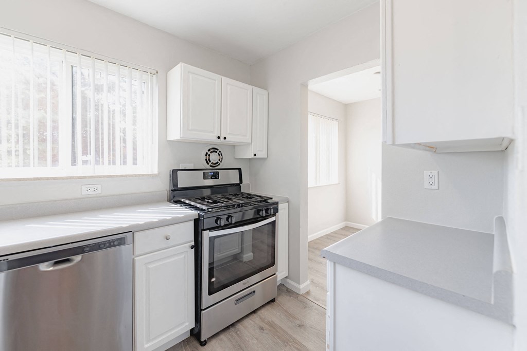 a white kitchen with stainless steel appliances and white cabinets