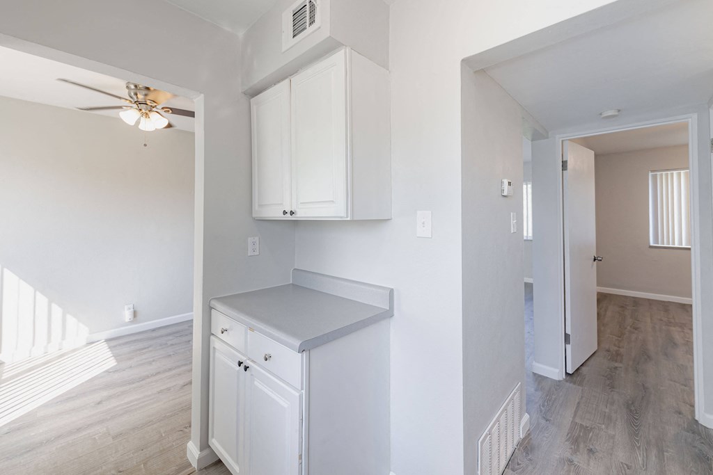 an empty kitchen with white cabinets and a ceiling fan