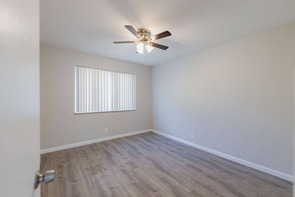 an empty bedroom with a ceiling fan and a window