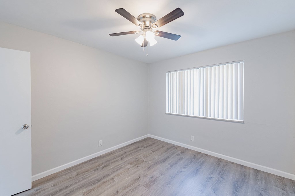 an empty bedroom with a ceiling fan and a window