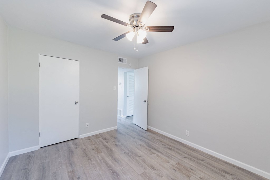 a spacious living room with white walls and a ceiling fan