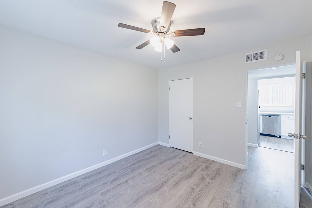 a living room with white walls and a ceiling fan